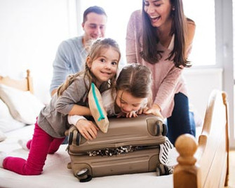 Familie mit Koffer im Hotelzimmer im Familienurlaub