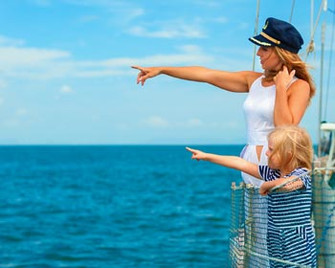 Mutter und Kind stehen an Schiffs-Reling und schauen und zeigen aufs Meer hinaus