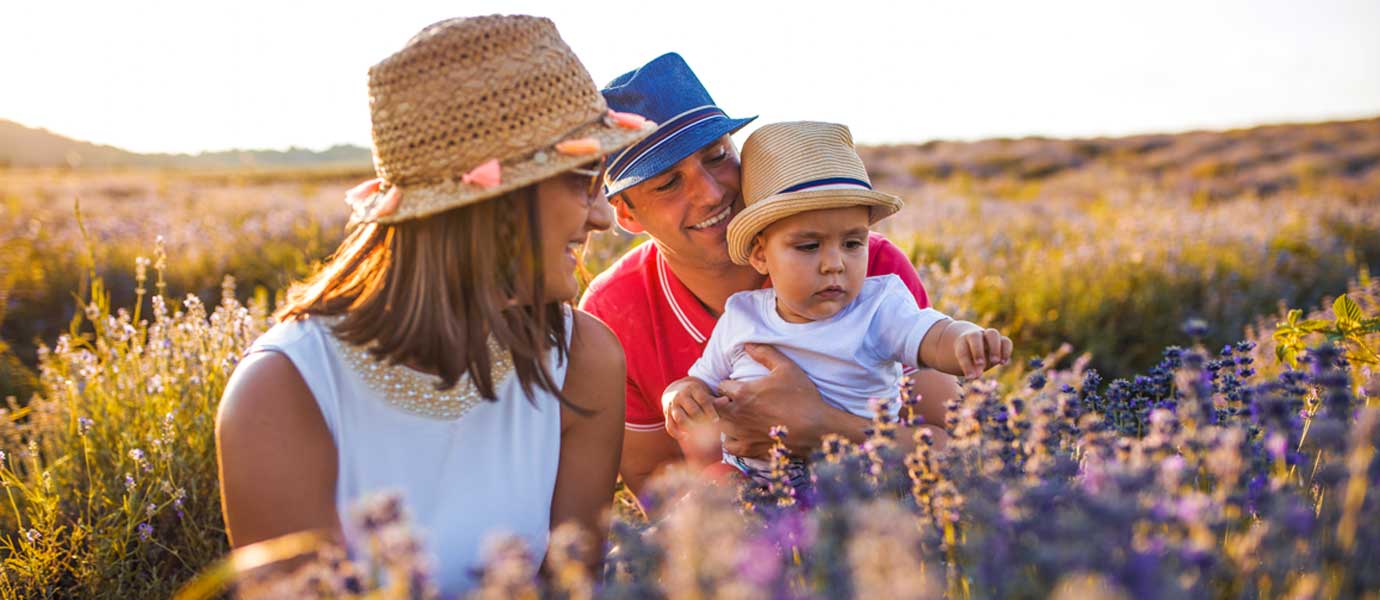 Glückliche Familie mit Baby im Lavendelfeld bei Sonnenuntergang