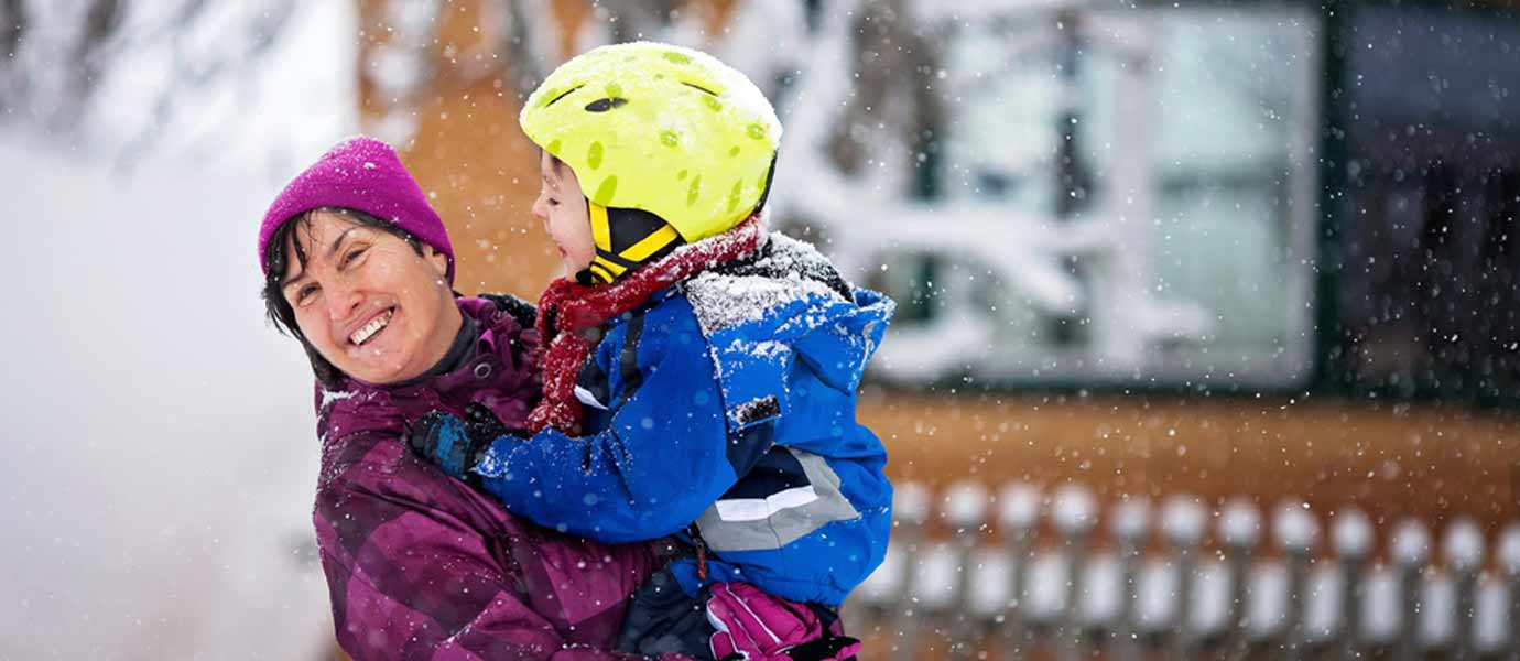Mutter und Sohn albern im Schnee herum.